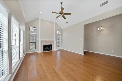 a view of a livingroom with a fireplace a ceiling fan and windows