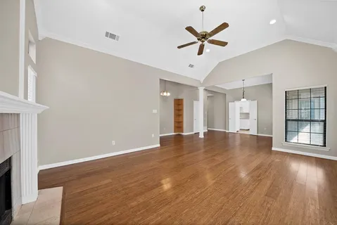 a view of an empty room with wooden floor and a window