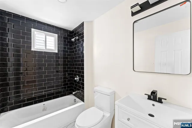 a bathroom with a bathtub shower sink vanity and toilet