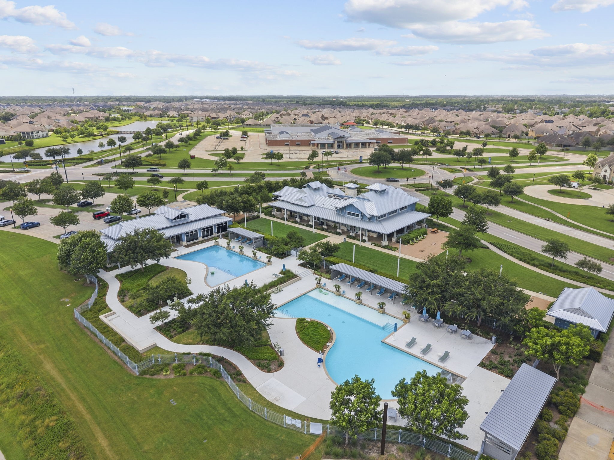 2011 Oak Leaf Court Manvel, TX 77578 - Photo 2 of 28 This photo showcases a community center with a large swimming pool, surrounded by manicured lawns and trees. The neighborhood features well-maintained roads and homes, offering a spacious and inviting environment.