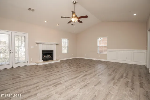 a view of an empty room with wooden floor and a window