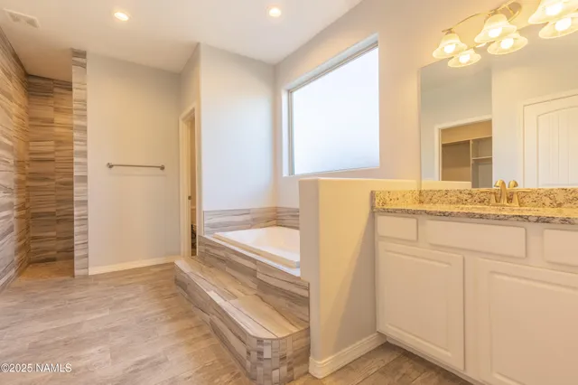 a bathroom with a tub and a view of bedroom