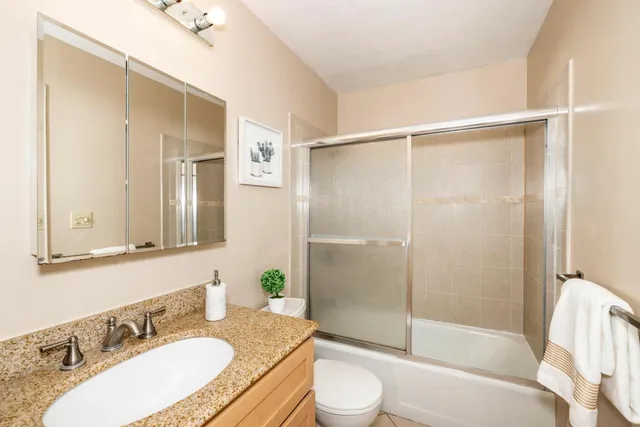 a bathroom with a granite countertop sink toilet and shower