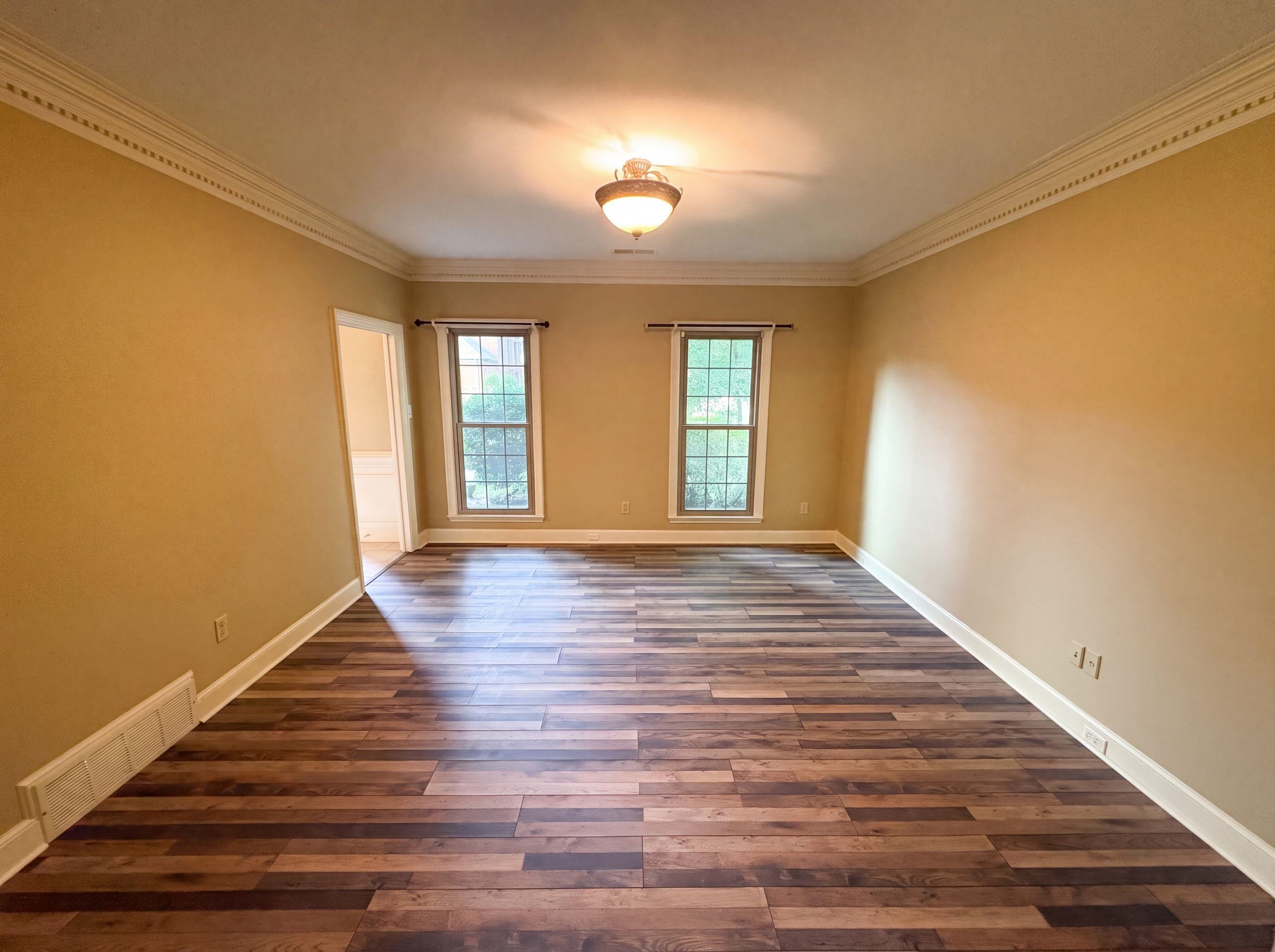 9424 Gotten Road Germantown, TN 38139 - Photo 6 of 27 Spacious room featuring wood-finish flooring, two windows with exterior views, crown molding, and a central ceiling light fixture