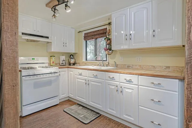 a kitchen with granite countertop white cabinets stainless steel appliances a sink and a window