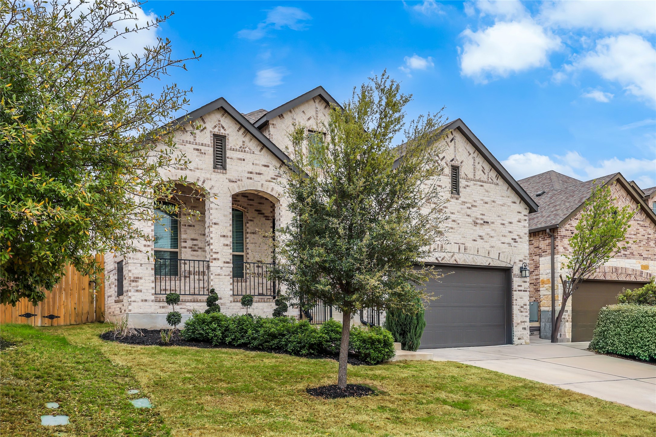 7705 Pace Ravine Drive Lago Vista, TX 78645 - Photo 2 of 40 French country home with a garage, brick siding, concrete driveway, and a porch