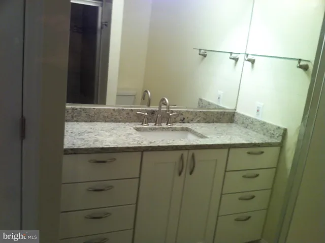a bathroom with a granite countertop sink and a mirror