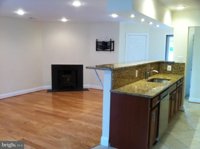 a bathroom with a granite countertop sink a toilet a mirror and bathtub