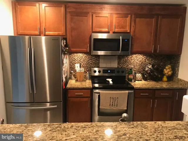 a kitchen with granite countertop a refrigerator stove and microwave