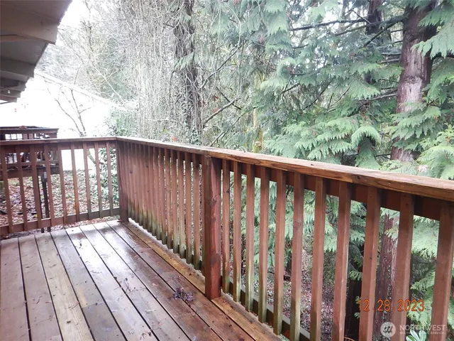 a balcony with wooden floor and trees in the back