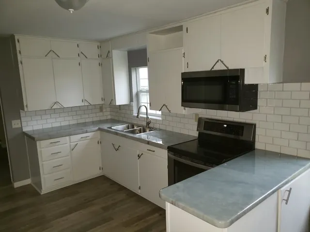 a kitchen with a sink dishwasher a stove and a microwave oven with cabinets