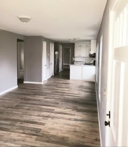a view of a kitchen with kitchen island granite countertop wooden floor and a refrigerator