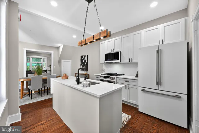 a white kitchen with a sink stainless steel appliances and wooden floor