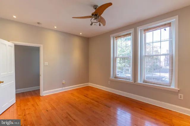 a view of empty room with wooden floor and fan