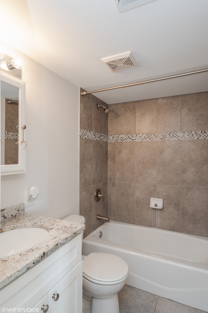 239 West 18th Street, Unit 2D Chicago, IL 60616 - Photo 5 of 10 a bathroom with a granite countertop bathtub shower sink vanity and toilet