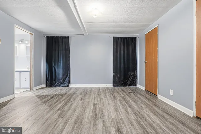 a view of an empty room with wooden floor and closet