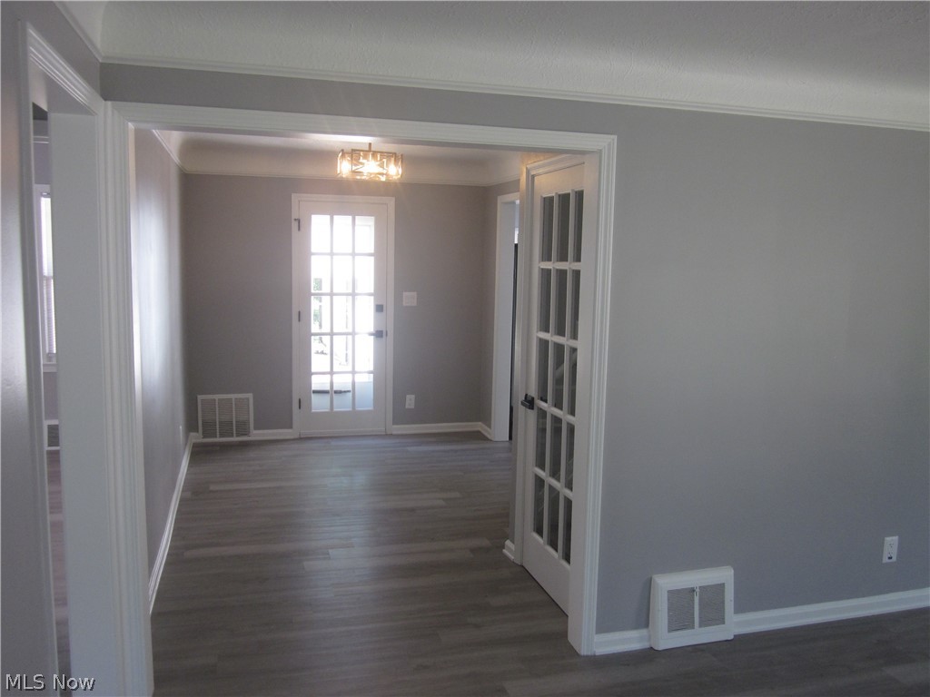 1810 Lorimer Road Cleveland, OH 44134 - Photo 13 of 47 Empty room with a notable chandelier, dark wood-type flooring, and ornamental molding