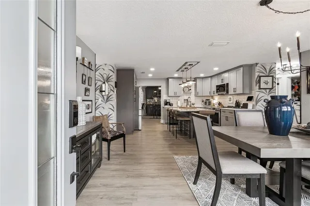 a kitchen with stainless steel appliances kitchen island granite countertop a table chairs and a refrigerator
