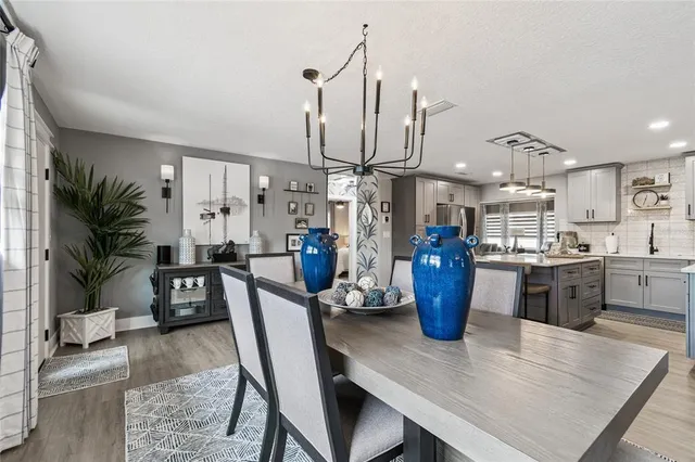 a kitchen with a refrigerator a stove a sink dishwasher a dining table and chairs with wooden floor