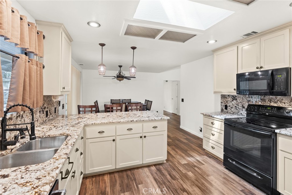 6350 Amherst Way Magalia, CA 95954 - Photo 12 of 25 a kitchen with stainless steel appliances kitchen island granite countertop a sink dishwasher stove and refrigerator with wooden floor