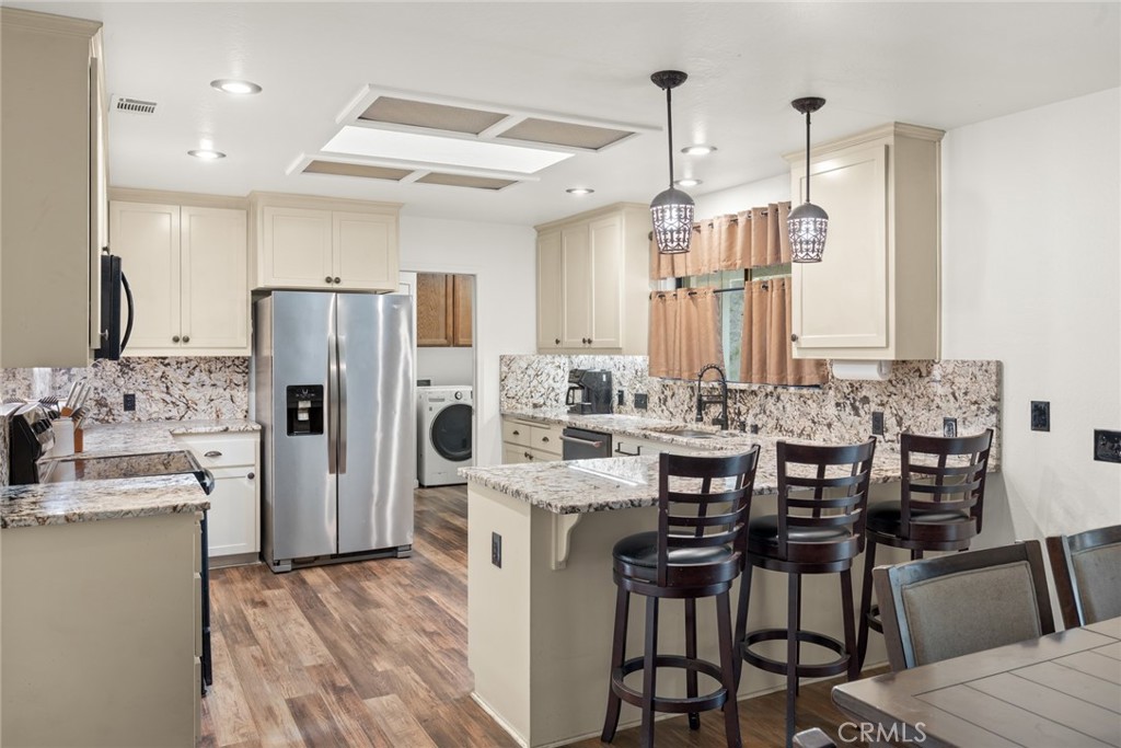 6350 Amherst Way Magalia, CA 95954 - Photo 9 of 25 a kitchen with stainless steel appliances kitchen island granite countertop a dining table chairs and white cabinets