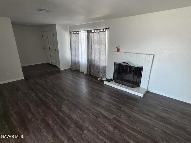 an empty room with wooden floor fireplace and windows