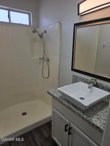 a bathroom with a granite countertop sink a mirror and shower