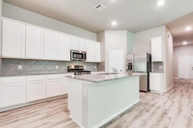 a kitchen with stainless steel appliances granite countertop a stove a sink and a refrigerator