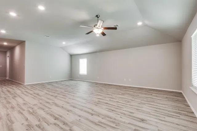a view of empty room with wooden floor and fan