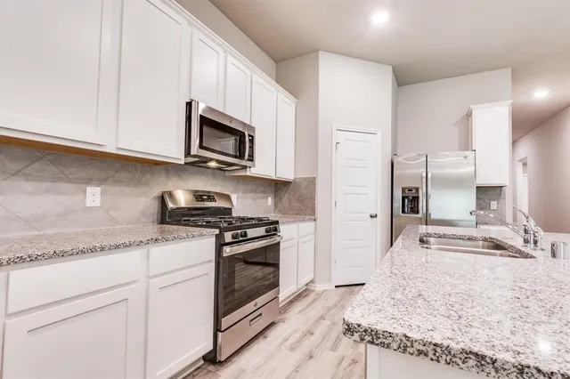 a kitchen with stainless steel appliances granite countertop a stove a sink and a microwave