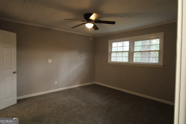 an empty room with ceiling fan and window