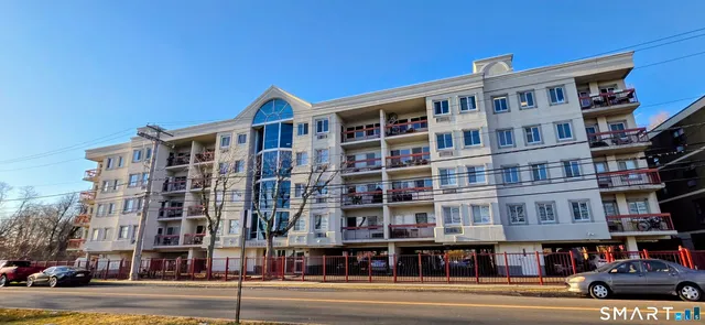 a front view of a building with lot of cars and trees