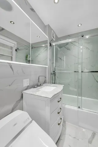 a bathroom with a sink toilet vanity and shower