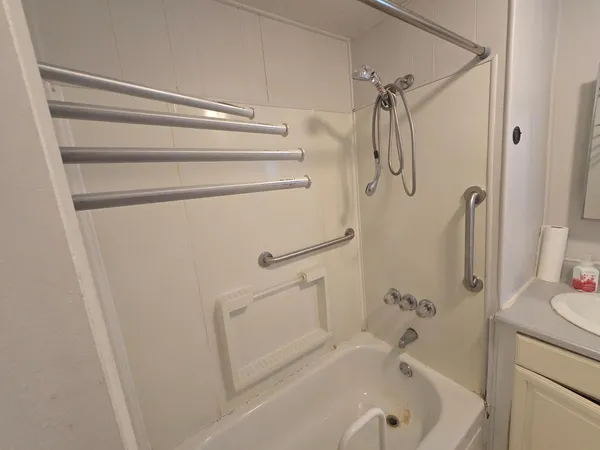 a bathroom with a tub shower vanity and a sink