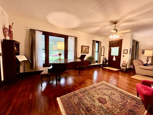 a living room with hardwood floor pool table and a large window