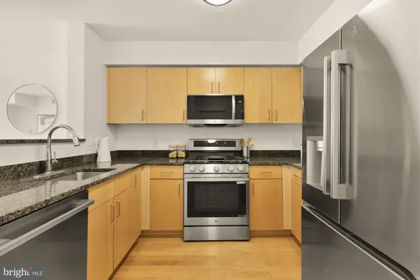 a kitchen with stainless steel appliances granite countertop a stove a sink and a microwave