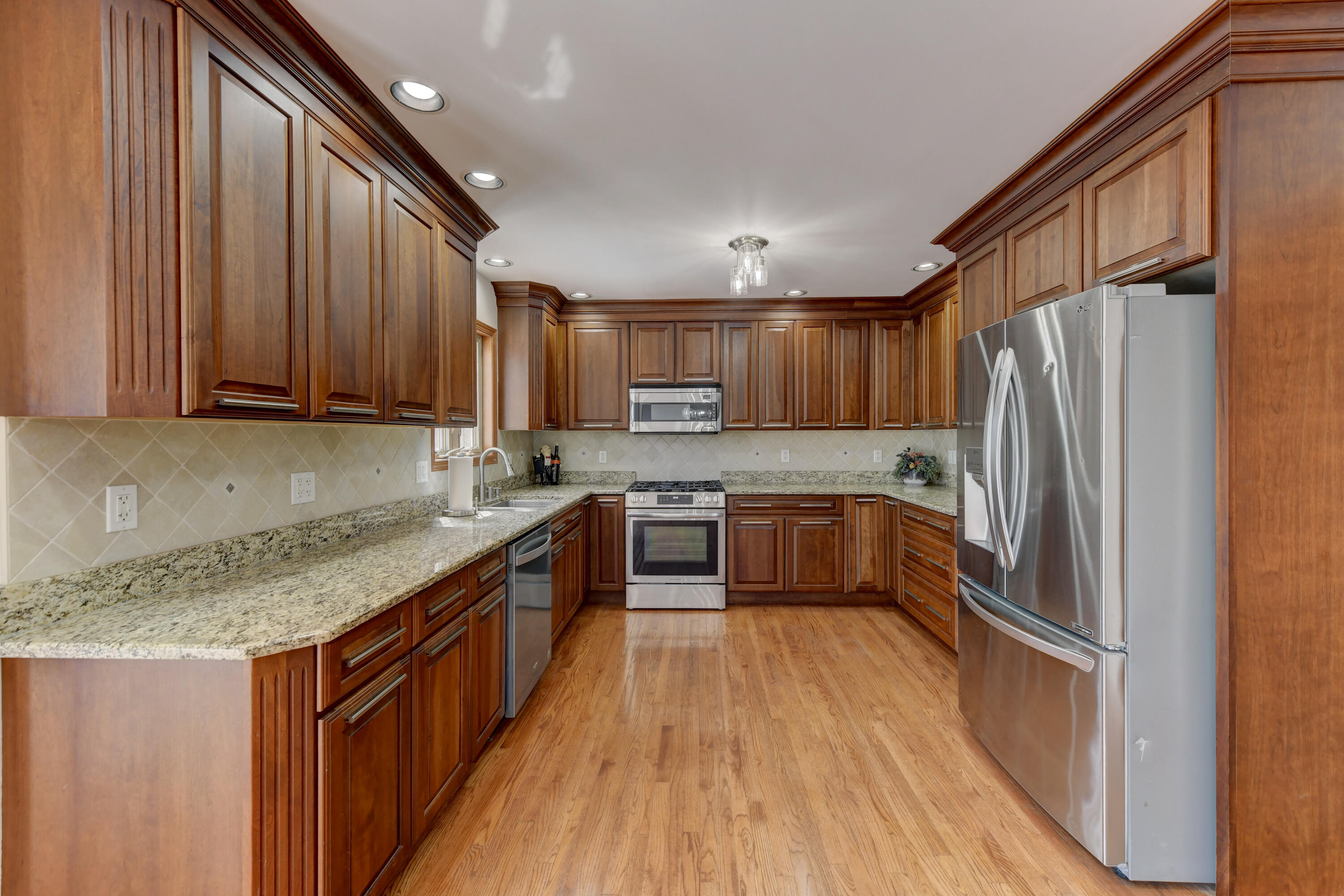 9575 Calumet Street Dyer, IN 46311 - Photo 32 of 53 a kitchen with granite countertop wooden floors stainless steel appliances a sink and a window