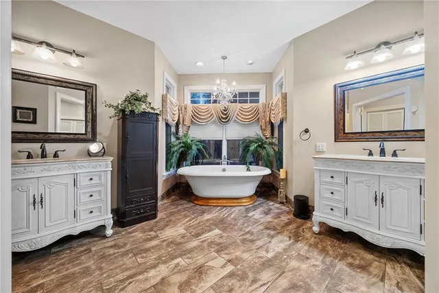 a spacious bathroom with a double vanity sink a mirror a bathtub and a window