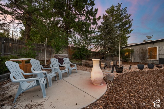 8678 Mount Majestic Road Sandy, UT 84093 - Photo 36 of 37 Outdoor concrete patio area featuring a privacy fence, mature trees, and a wood chip ground cover