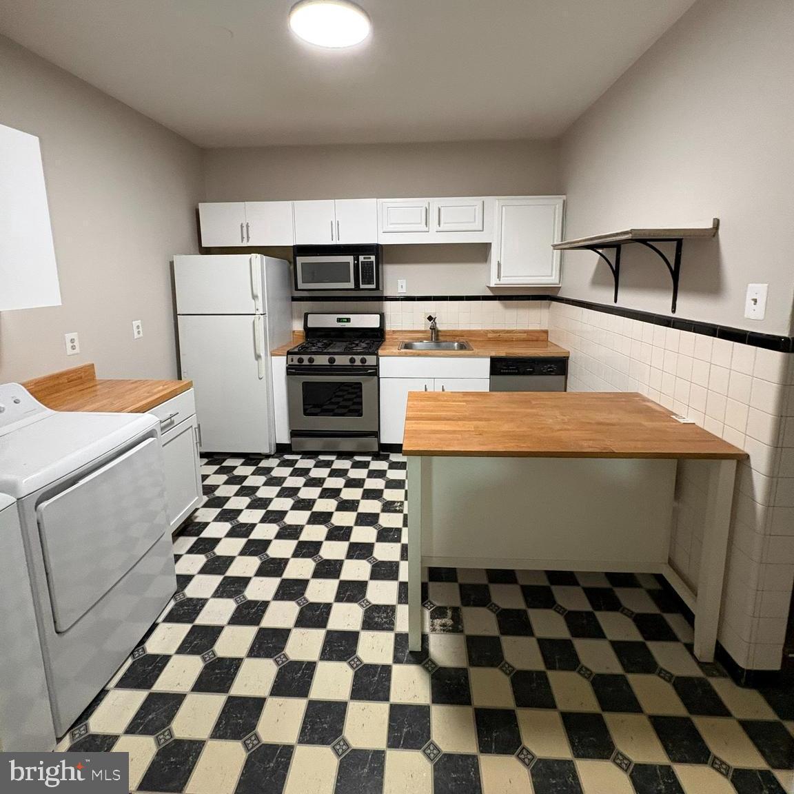 a kitchen with a checkered floor and white cabinets
