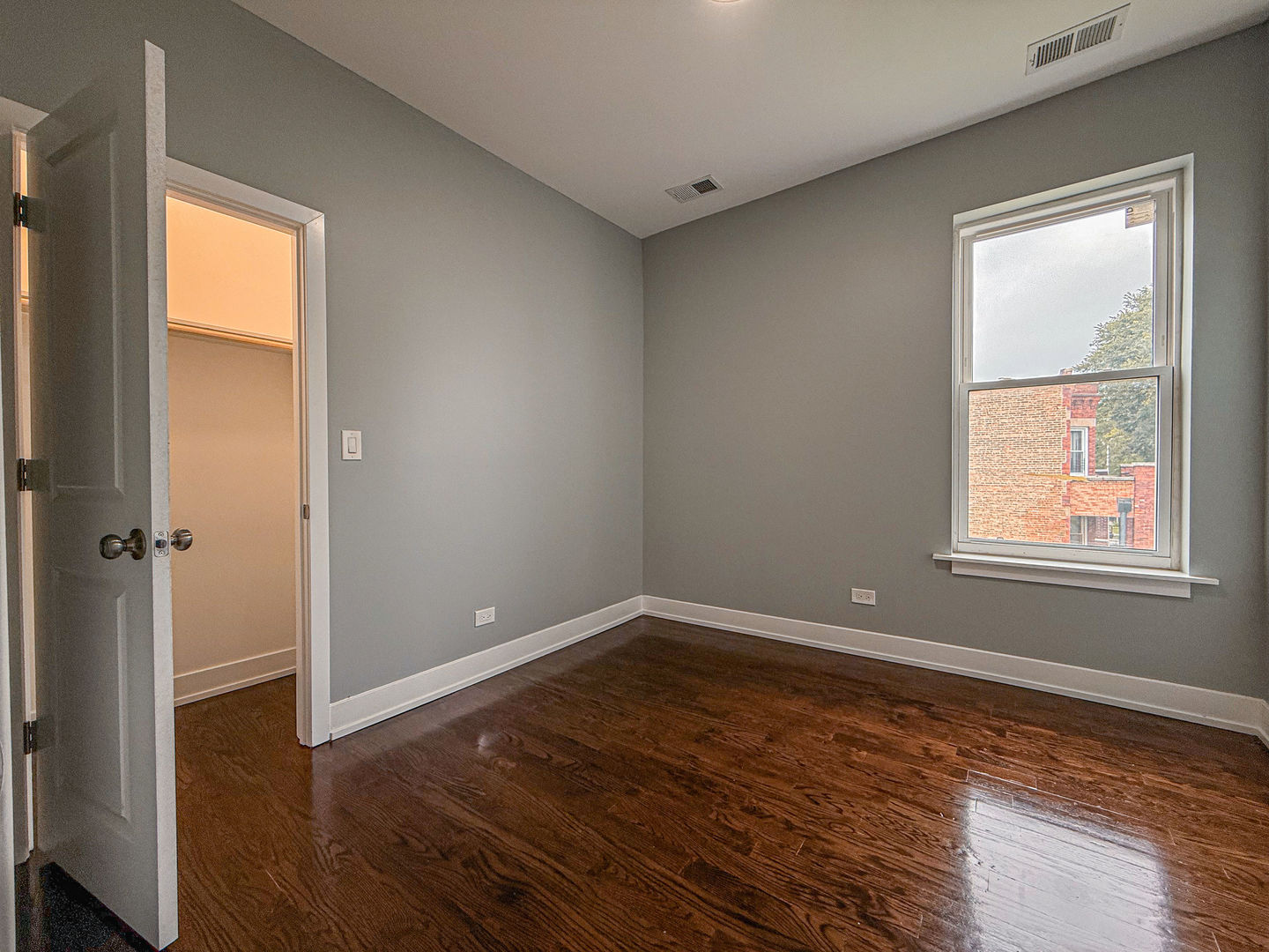 4817 West Jackson Boulevard, Unit 2 Chicago, IL 60644 - Photo 9 of 20 an empty room with wooden floor and windows