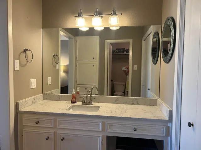 a bathroom with a granite countertop sink and a mirror