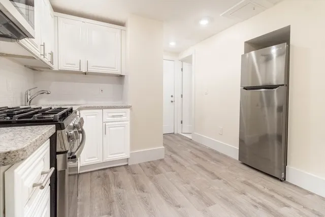 a kitchen with a refrigerator a stove and white cabinets