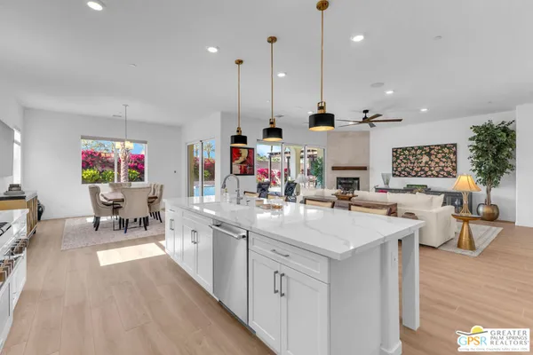 a large kitchen with kitchen island a stove a sink a refrigerator and white cabinets with wooden floor