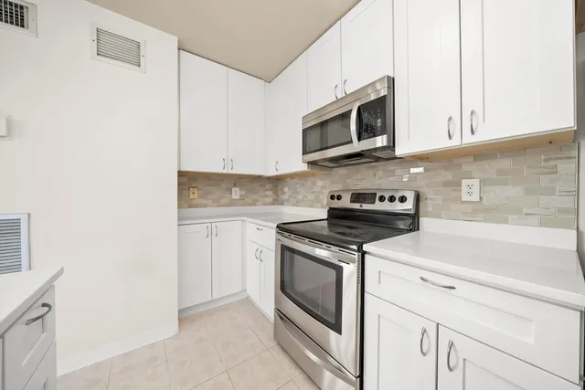 a kitchen with stainless steel appliances granite countertop white cabinets a stove top oven with wooden floor