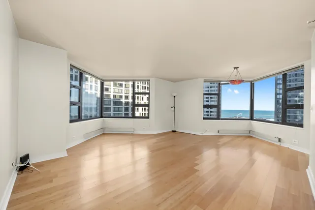 a view of an empty room with a window and wooden floor