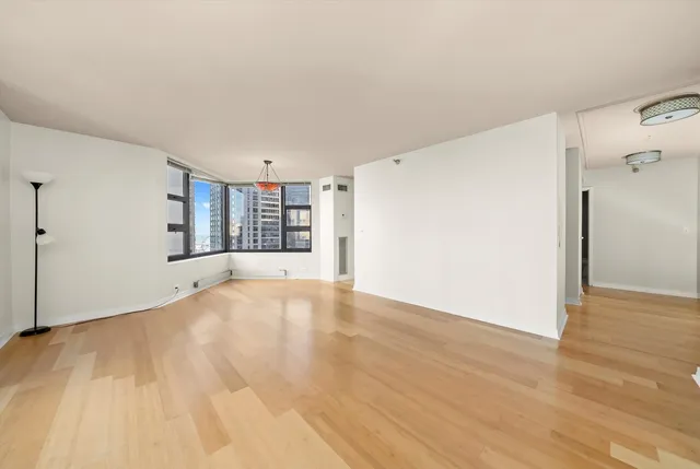 a view of an empty room with a window and wooden floor