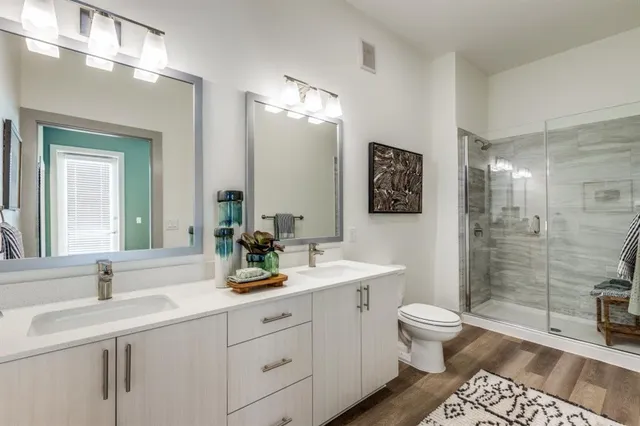 a bathroom with a double vanity sink toilet and shower
