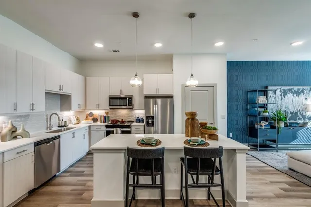 a kitchen with sink a refrigerator and chairs