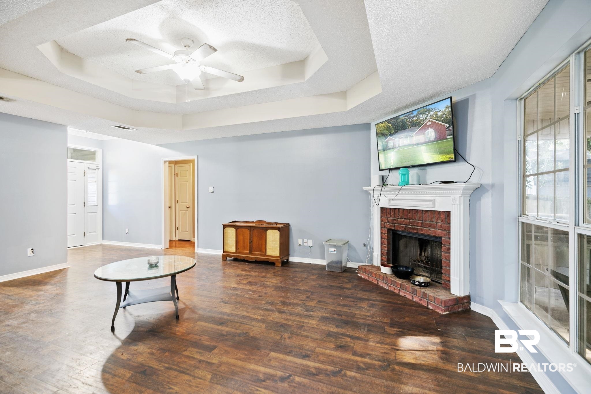 10550 Patrick Avenue Grand Bay, AL 36541 - Photo 11 of 43 Living room featuring wood-type flooring, a raised ceiling, a brick fireplace, and ceiling fan